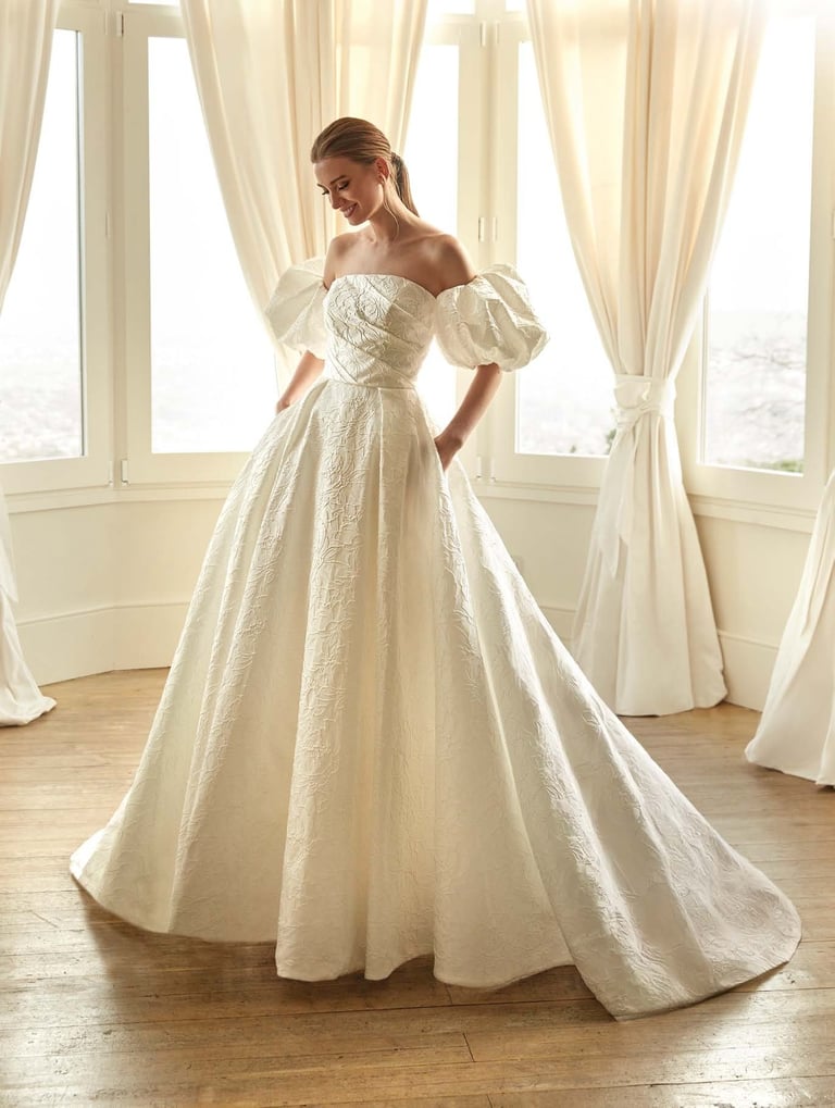 Novia con vestido ivoire con mangas puff en habitación con cortinas