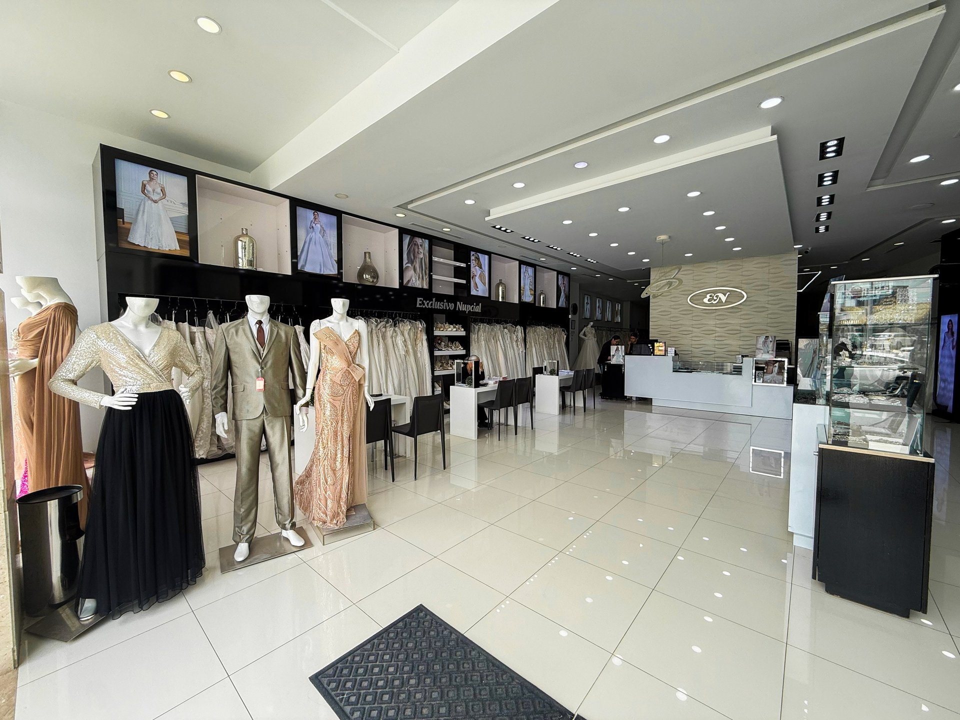 Interior moderno de boutique Exclusivo Nupcial con percheros de vestidos y piso de loseta blanca